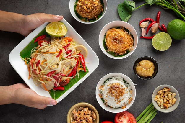 Ensalada de papaya servida con fideos de arroz y ensalada de verduras Decorada con ingredientes de la comida tailandesa.