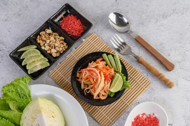 Ensalada de papaya tailandesa en un plato blanco con arroz y camarones secos