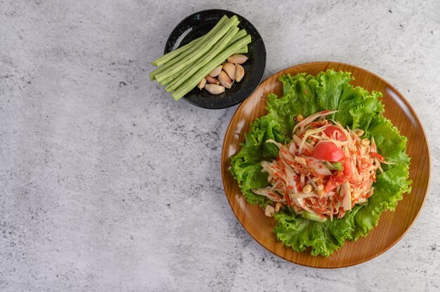 Ensalada de papaya tailandesa en un plato blanco con judías largas, ajo y col blanca