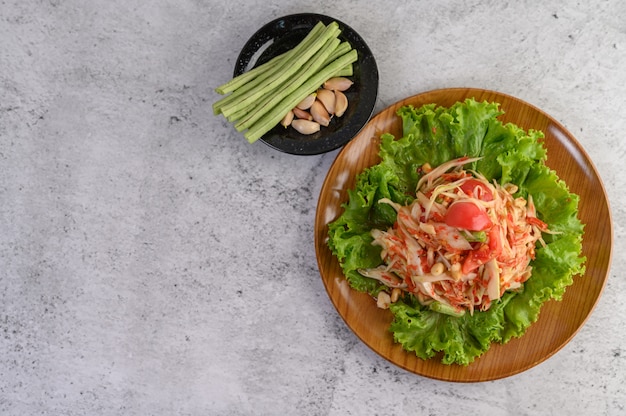 Ensalada de papaya tailandesa en un plato blanco con judías largas, ajo y col blanca