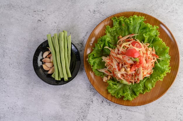 Ensalada de papaya tailandesa en un plato blanco con judías largas, ajo y col blanca