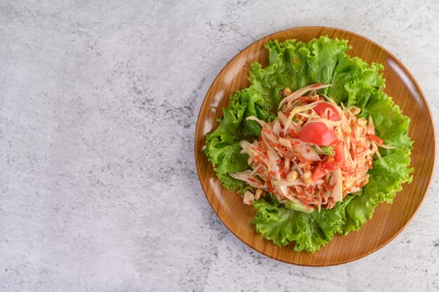 Ensalada de papaya tailandesa en un plato de madera