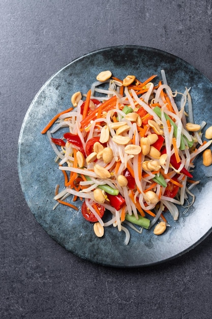 Foto gratuita ensalada de papaya verde som tam thai sobre fondo de pizarra negra