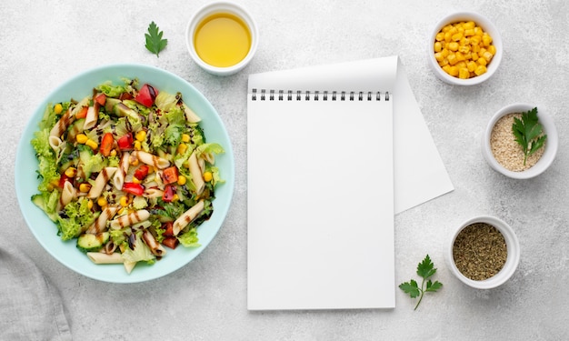 Ensalada de pasta vista superior con vinagre balsámico y bloc de notas en blanco