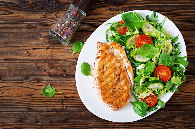 Ensalada de pechuga de pollo a la parrilla y vegetales frescos: tomates, pepinos y hojas de lechuga. Ensalada de pollo. Comida sana. Endecha plana. Vista superior