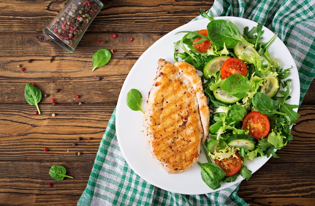 Ensalada de pechuga de pollo a la parrilla y vegetales frescos: tomates, pepinos y hojas de lechuga. Ensalada de pollo. Comida sana. Endecha plana. Vista superior