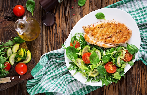 Ensalada de pechuga de pollo a la parrilla y vegetales frescos: tomates, pepinos y hojas de lechuga. Ensalada de pollo. Comida sana. Endecha plana. Vista superior