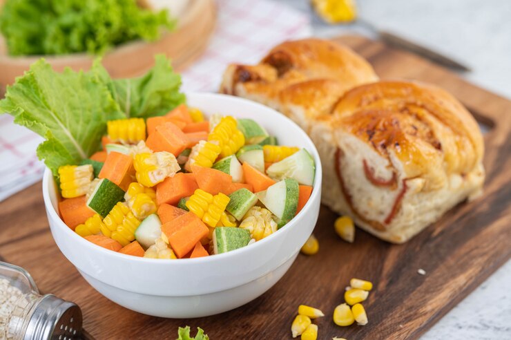 Foto gratuito ensalada de pepino, maíz, zanahoria y lechuga en una taza blanca.