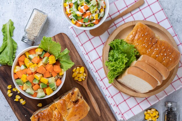 Ensalada de pepino, maíz, zanahoria y lechuga en una taza blanca.