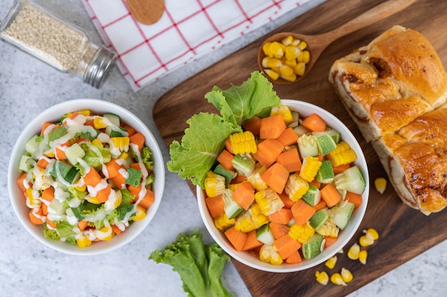 Foto gratuita ensalada de pepino, maíz, zanahoria y lechuga en una taza blanca.