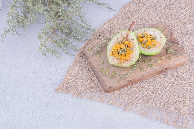 Ensalada de pera pelada con zanahoria y semillas de calabaza sobre una tabla de madera