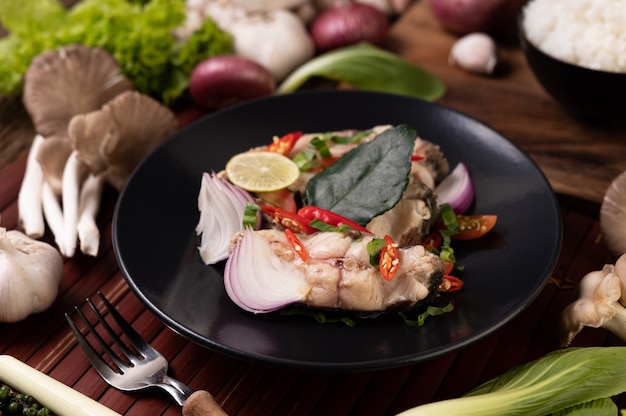 Ensalada de pescado con lima, ají, limoncillo, cebolla, cebolla morada, perejil y hojas de lima kaffir en el plato