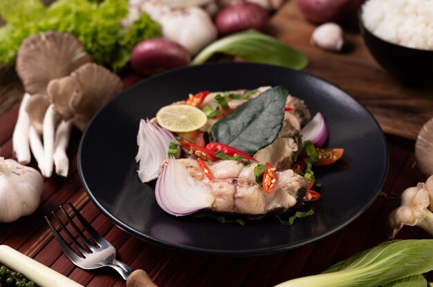 Ensalada de pescado con lima, ají, limoncillo, cebolla, cebolla morada, perejil y hojas de lima kaffir en el plato