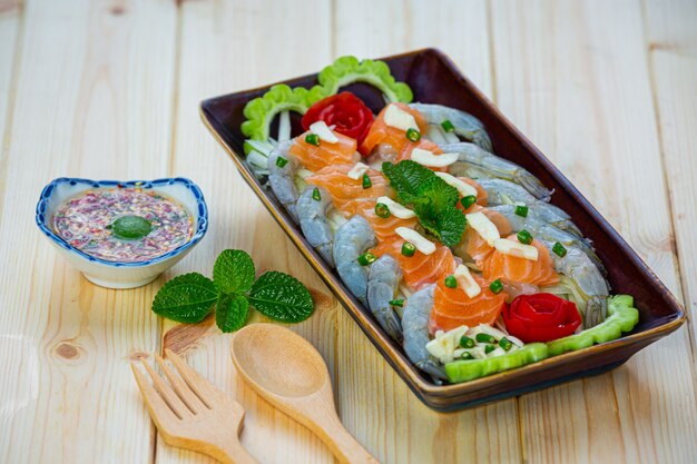 Ensalada picante de camarones y salmón sobre superficie de madera