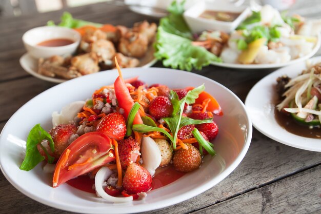 Ensalada picante de fresa en plato blanco, menú Spacial en Tailandia