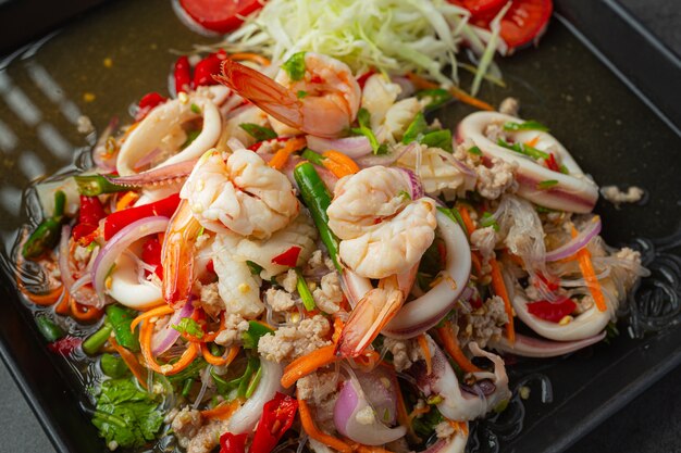 Ensalada picante de mariscos mixtos con ingredientes de comida tailandesa.