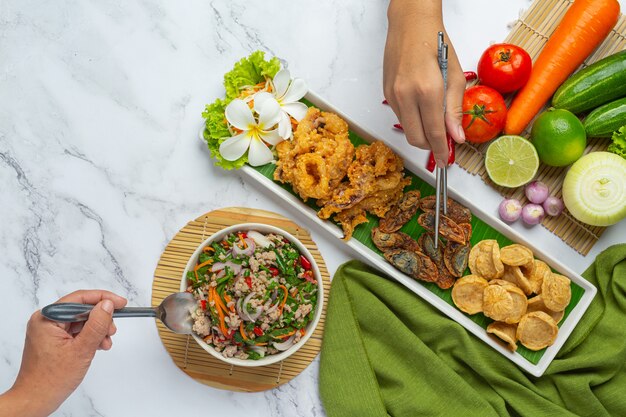 Ensalada picante mixta con salchicha vietnamita, huevo en conserva y calamar crujiente, comida tailandesa.