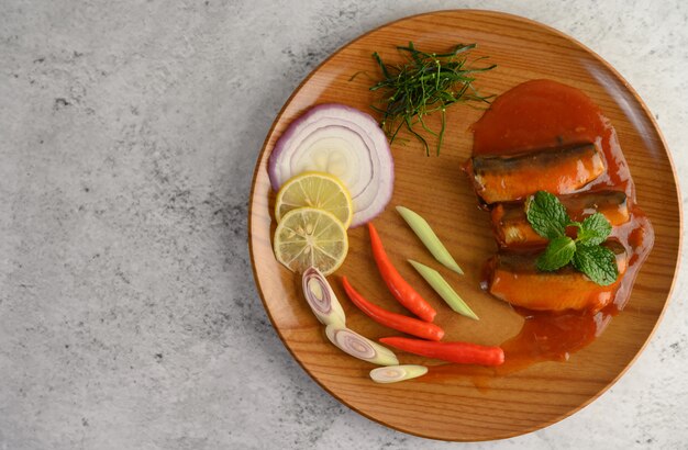 Ensalada picante de sardina en salsa de tomate en bandeja de madera