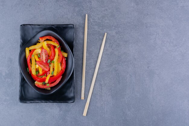 Ensalada de pimiento colorido con tomates cherry sobre superficie azul