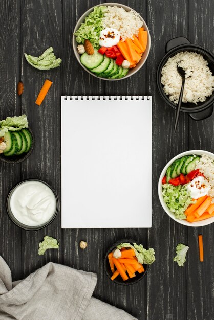 Ensalada plana con cuscús y cuaderno en blanco