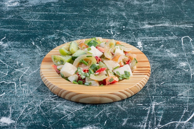 Ensalada en un plato de madera con ingredientes picados y hierbas.