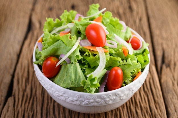 Ensalada en el recipiente en la mesa de madera.