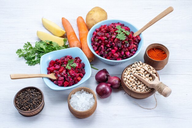 Ensalada de remolacha fresca con verduras en rodajas dentro de placas azules con ingredientes en el escritorio de luz, ensalada de verduras comida comida saludable snack