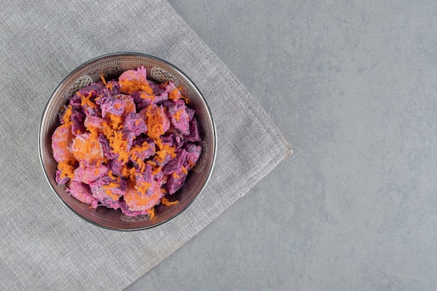 Ensalada de remolacha morada con rodajas de zanahoria y crema agria en un recipiente metálico