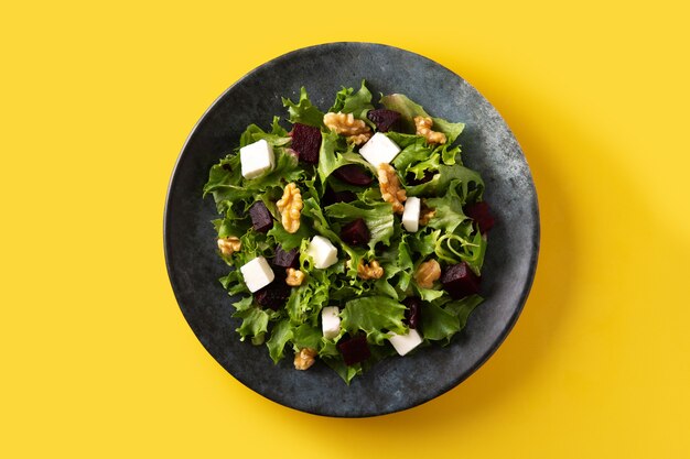 Ensalada de remolacha con queso feta, lechuga y nueces sobre fondo amarillo