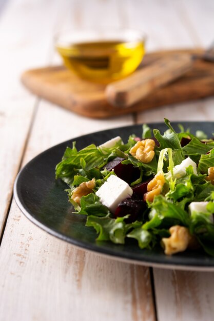 Ensalada de remolacha con queso feta, lechuga y nueces sobre mesa de madera rústica