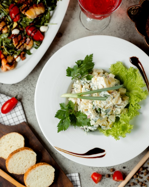 Foto gratuita ensalada rusa sobre la mesa con pan