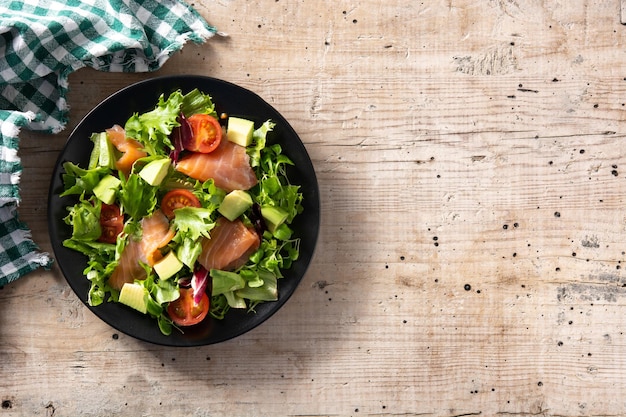 Ensalada de salmón y aguacate en mesa de madera rústica