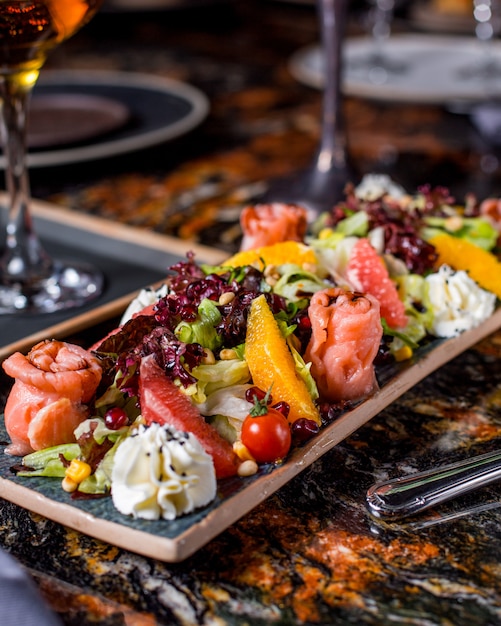 Ensalada de salmón con lechuga, tomate, maíz, naranja, pomelo, granada y nata