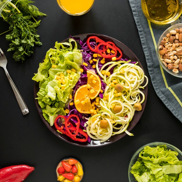 Ensalada saludable adornada en placa con frutos secos dispuestos sobre fondo negro