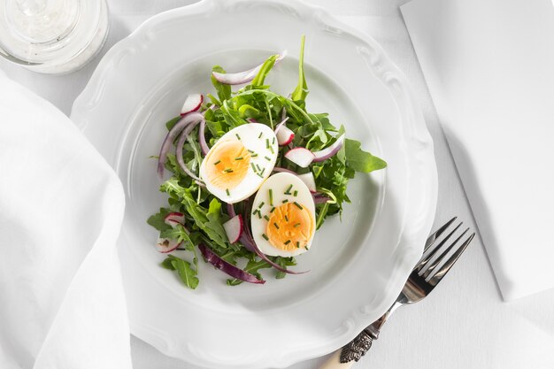 Ensalada saludable con huevo en un arreglo de plato blanco