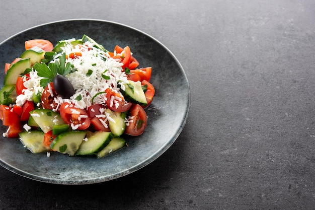 Ensalada shopka tradicional búlgara con tomate, pepino y queso sirene búlgaro sobre fondo negro