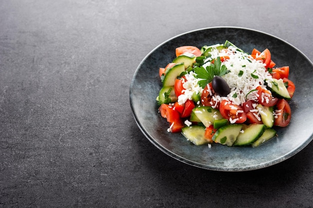 Ensalada shopka tradicional búlgara con tomate, pepino y queso sirene búlgaro sobre fondo negro