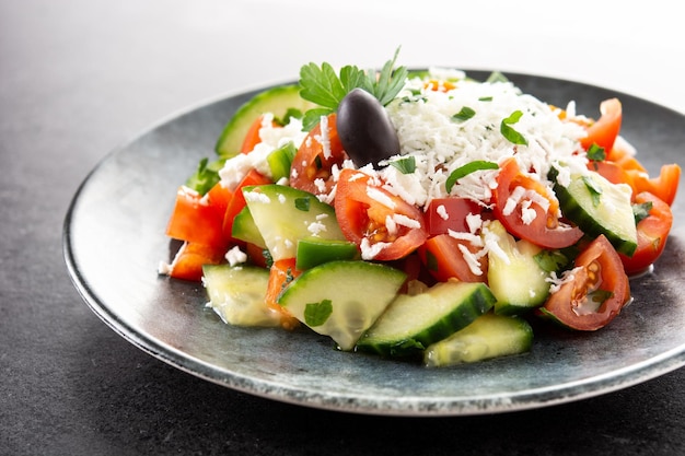 Ensalada shopka tradicional búlgara con tomate, pepino y queso sirene búlgaro sobre fondo de pizarra negra