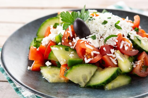 Ensalada shopka tradicional búlgara con tomate, pepino y queso sirene búlgaro sobre mesa de madera