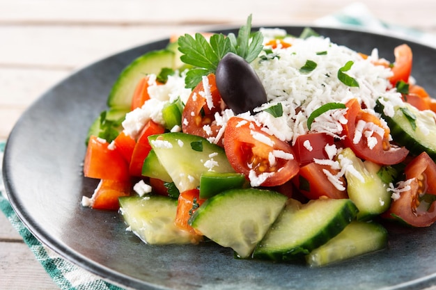 Ensalada shopka tradicional búlgara con tomate, pepino y queso sirene búlgaro sobre mesa de madera