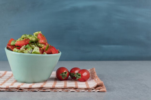 Ensalada en taza azul con una mezcla de frutas y verduras picadas.