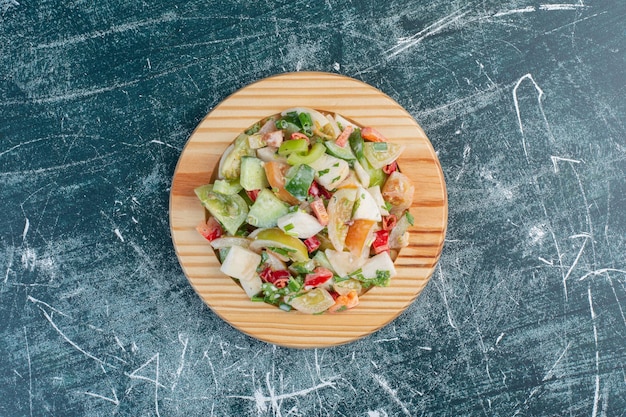 Foto gratuita ensalada de temporada con ingredientes mixtos en bandeja de madera.