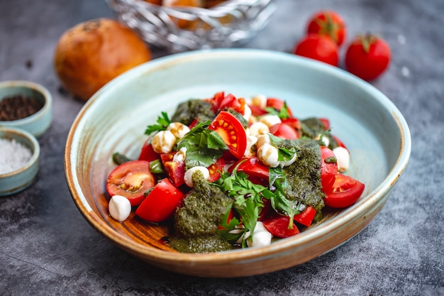 Foto gratuita ensalada de tomate y mozzarella con salsa de pesto y perejil