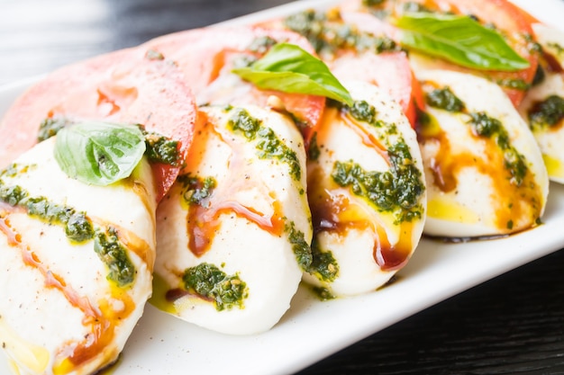 Ensalada de tomate y queso mozzarella en plato blanco