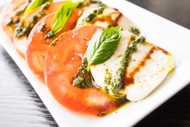 Ensalada de tomate y queso mozzarella en plato blanco