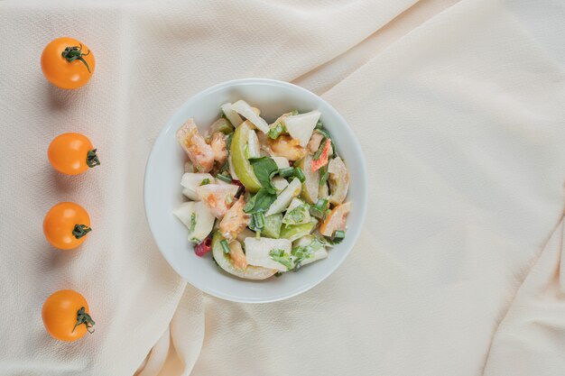 Ensalada de tomate verde picado con hierbas y especias sobre superficie de hormigón