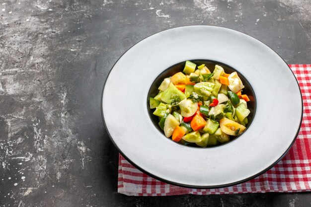 Ensalada de tomate verde de vista inferior en placa ovalada sobre fondo oscuro