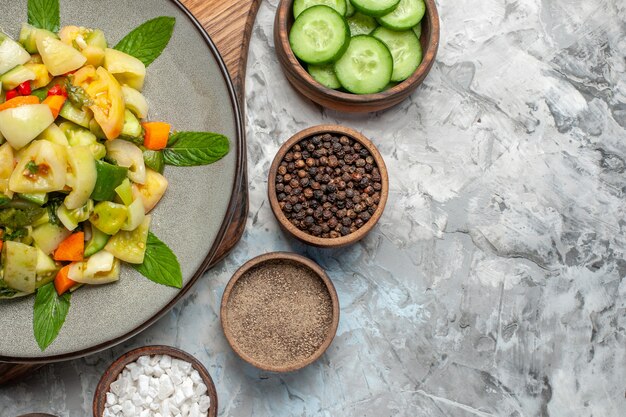 Ensalada de tomate verde de vista superior en especias de placa ovalada en tazones sobre superficie oscura