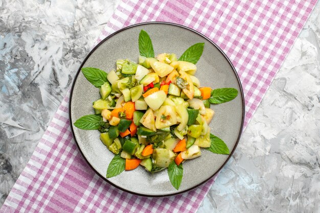 Ensalada de tomate verde vista superior en mantel rosa placa ovalada sobre fondo gris