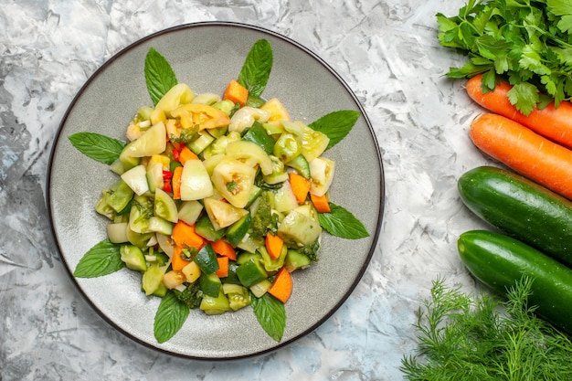 Foto gratuita ensalada de tomate verde vista superior en verduras placa ovalada sobre fondo oscuro